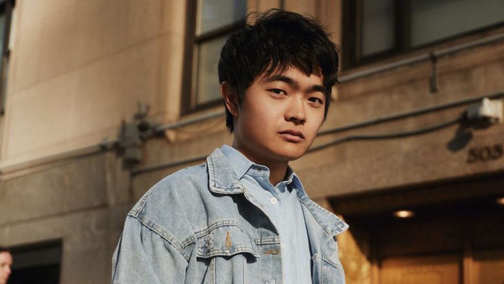 "Ben Wang, wearing a denim jacket and standing outside in an urban setting, gives a calm, confident look toward the camera. He is set to join the cast of Karate Kid: Legends"