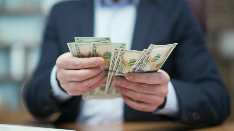 Close up hands of business man investor counting dollars banknotes at desk in modern office Successful entrepreneur holding money and rejoices at good earnings income salary investment at workplace