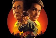 "Poster for Karate Kid Legends featuring Jackie Chan, Ralph Macchio, and Ben Wang. Chan and Macchio stand in the background with serious expressions, while Wang, in a martial arts stance, is in the foreground. The sunset-lit skyline of New York City is seen at the bottom, with a red-orange sun creating a dramatic backdrop.